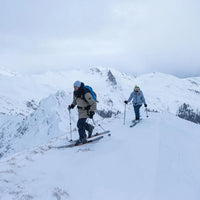 Två turåkare på en snötäckt bergskam