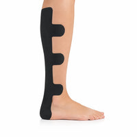 Svart förklippt kinesiologitejp med flexibel design applicerad längs sidan av vaden och underbenet.
