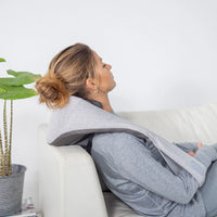 Kvinna lutar sig tillbaka i en soffa med Sharper Image Realtouch runt nacken