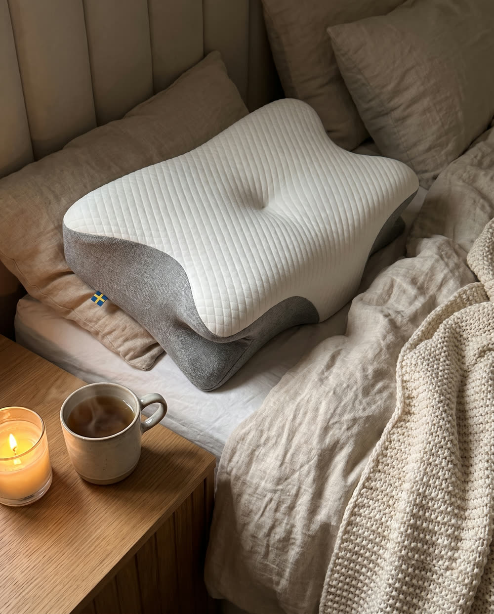 SleepEase-nukkumistyyny sängyllä, neulottu torkkupeitto ja teetä yöpöydällä